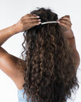 France Luxe long, white barrette for women pictured holding curly, brown hair in a half up hairstyle.