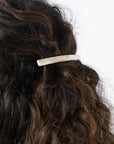 France Luxe long French barrette for women pictured holding curly, brown hair in a half up hairstyle.