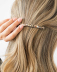 France Luxe long French barrette for women pictured holding straight, blonde hair in a half up hairstyle.
