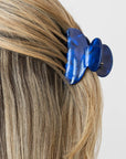 France Luxe small French claw hair clip for women pictured holding straight, blonde hair in a half up hairstyle.