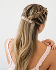 France Luxe medium French barrette for women pictured holding straight, blonde hair in a braided hairstyle.