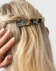 France Luxe medium French barrette for women pictured holding straight, blonde hair in a braided hairstyle.