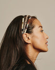 France Luxe thin headband in a Natural Horn, Black Horn, and Damier color, pictured holding straight, black hair in a loose hairstyle.