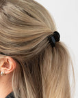 France Luxe mini French claw hair clip for women pictured holding straight, blonde hair in a half up hairstyle.