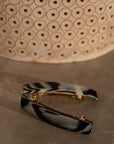 Two Classic French Barrettes in a horn inspired black & cream pattern, pictured next to a basket.