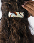 France Luxe large French barrette for women pictured holding curly, brown hair in a half up hairstyle.