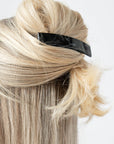 France Luxe medium French barrette for women pictured holding straight, blonde hair in a half up hairstyle.