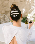Woman with straight, brown hair styled in an updo with a France Luxe small barrette, marbled ivory white.