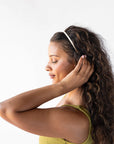 France Luxe marbled ivory white headband for women pictured holding curly, brown hair in a loose hairstyle.