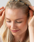 France Luxe thin headband in a golden sand and rich brown color, pictured holding straight, blonde hair in a loose hairstyle.