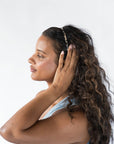 France Luxe thin headband in a Ivory Tortoise Shell color, pictured holding curly, brown hair in a loose hairstyle.