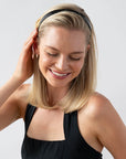 France Luxe classic black headband for women pictured holding straight, blonde hair in a loose hairstyle.