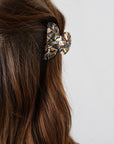 France Luxe small, grey claw hair clip for women pictured holding straight, brown hair in a casual half up hairstyle.
