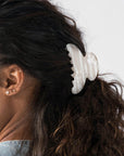 France Luxe medium French claw hair clip for women pictured holding curly, brown hair in a half up hairstyle.
