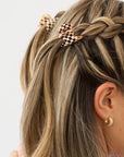 France Luxe mini French claw hair clip for women pictured holding straight, blonde hair in a braided hairstyle.