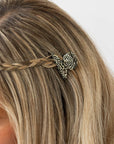 France Luxe mini French claw hair clip for women pictured holding straight, blonde hair in a braided hairstyle.