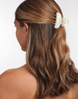 France Luxe small French claw hair clip for women pictured holding straight, brown hair in a half up hairstyle.