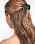 France Luxe small, black claw hair clip for women pictured holding straight, brown hair in a casual half up hairstyle.