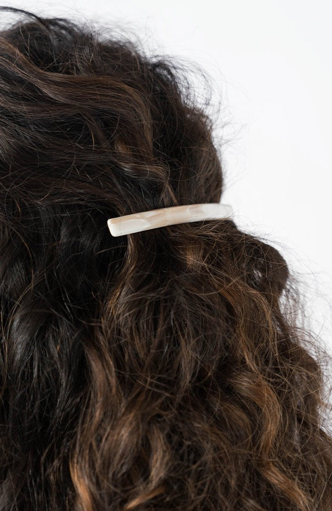 France Luxe long French barrette for women pictured holding curly, brown hair in a half up hairstyle.