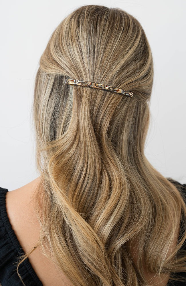 France Luxe long, grey barrette for women pictured holding wavy, blonde hair in a half up hairstyle.