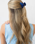 France Luxe small, navy blue claw hair clip for women pictured holding straight, blonde hair in a half up hairstyle.