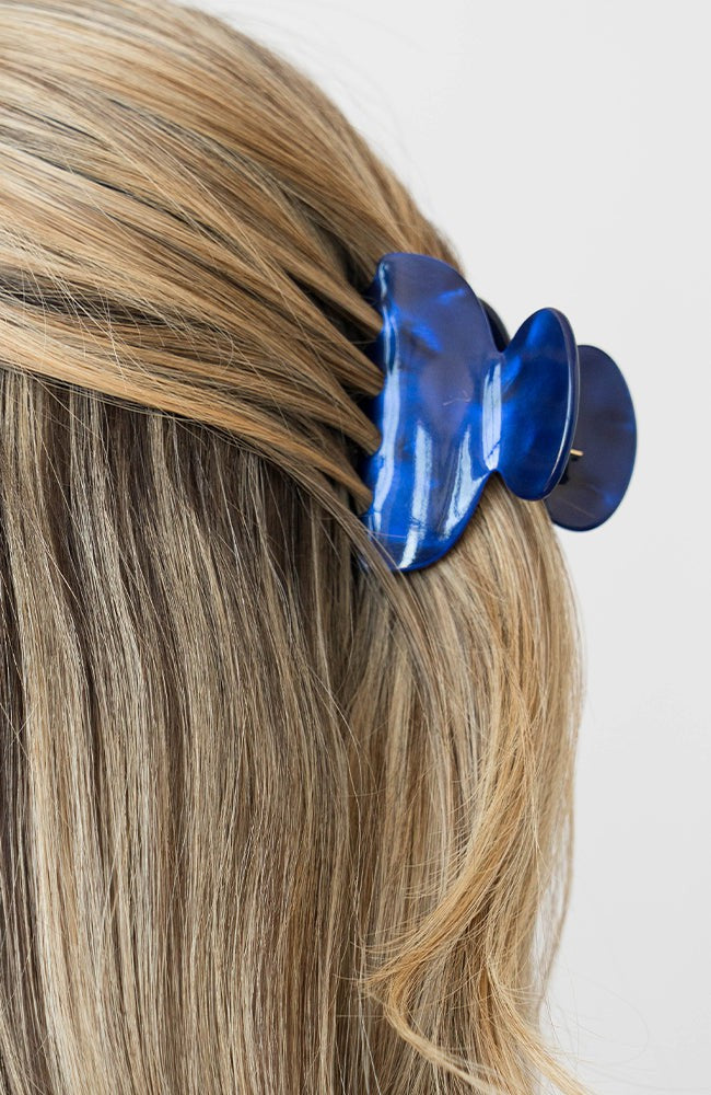 France Luxe small French claw hair clip for women pictured holding straight, blonde hair in a half up hairstyle.