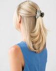 France Luxe small, silver claw hair clip for women pictured holding straight, blonde hair in a casual half up hairstyle.
