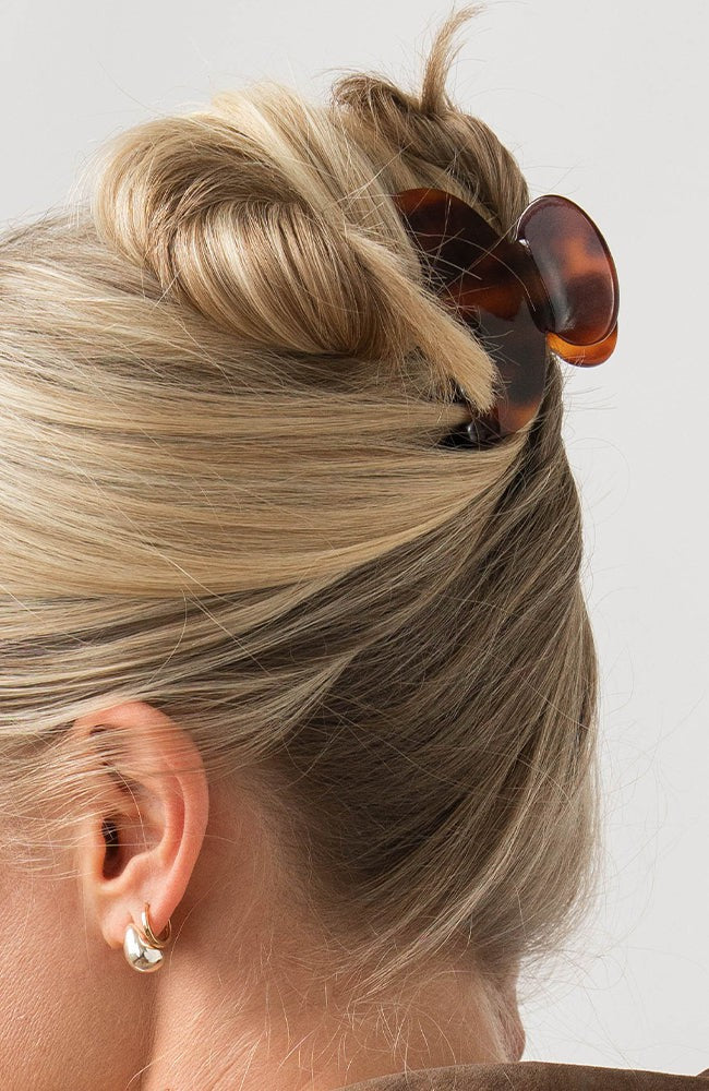 Woman with straight, blonde hair styled in an updo with a France Luxe small claw hair clip, rich amber and mahogany brown.
