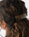 France Luxe large French barrette for women pictured holding curly, brown hair in a half up hairstyle.