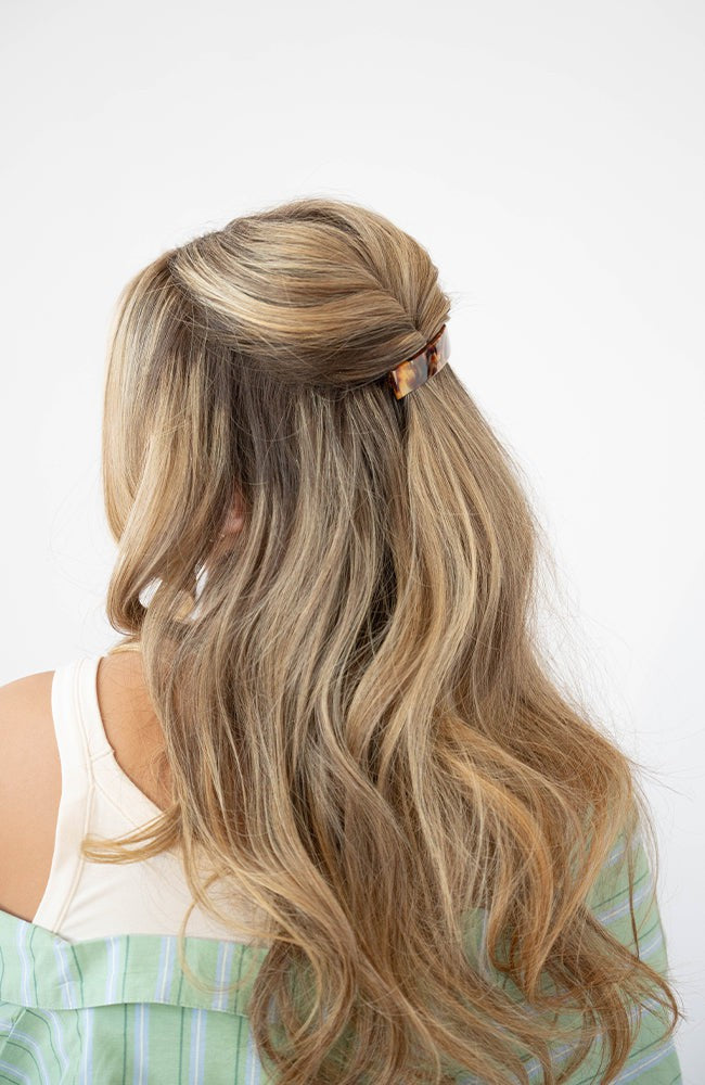 France Luxe medium French barrette for women pictured holding straight, blonde hair in a braided hairstyle.