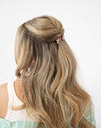 France Luxe medium French barrette for women pictured holding straight, blonde hair in a braided hairstyle.