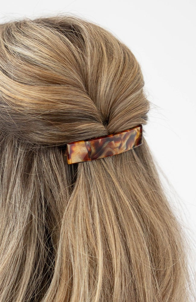 France Luxe medium French barrette for women pictured holding straight, blonde hair in a braided hairstyle.