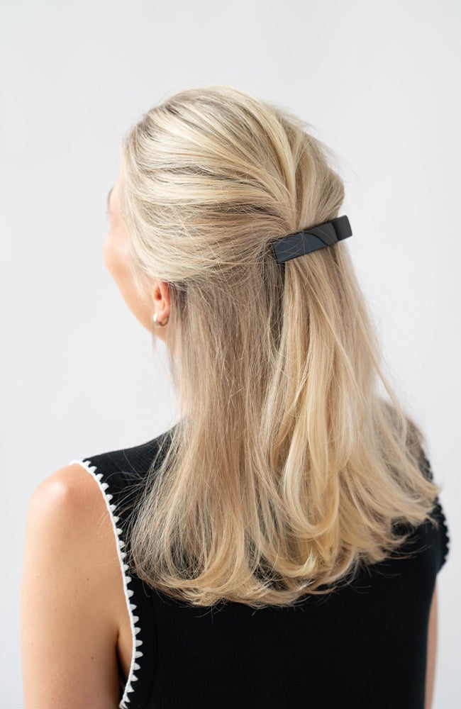 France Luxe medium French barrette for women pictured holding straight, blonde hair in a half up hairstyle.