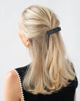 France Luxe medium French barrette for women pictured holding straight, blonde hair in a half up hairstyle.
