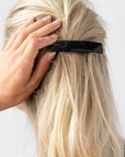 France Luxe medium, black barrette for women pictured holding straight, blonde hair in a half up hairstyle.