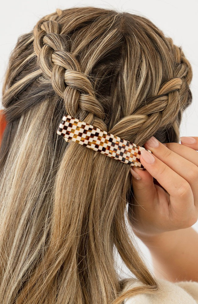 France Luxe medium French barrette for women pictured holding straight, blonde hair in a braided hairstyle.