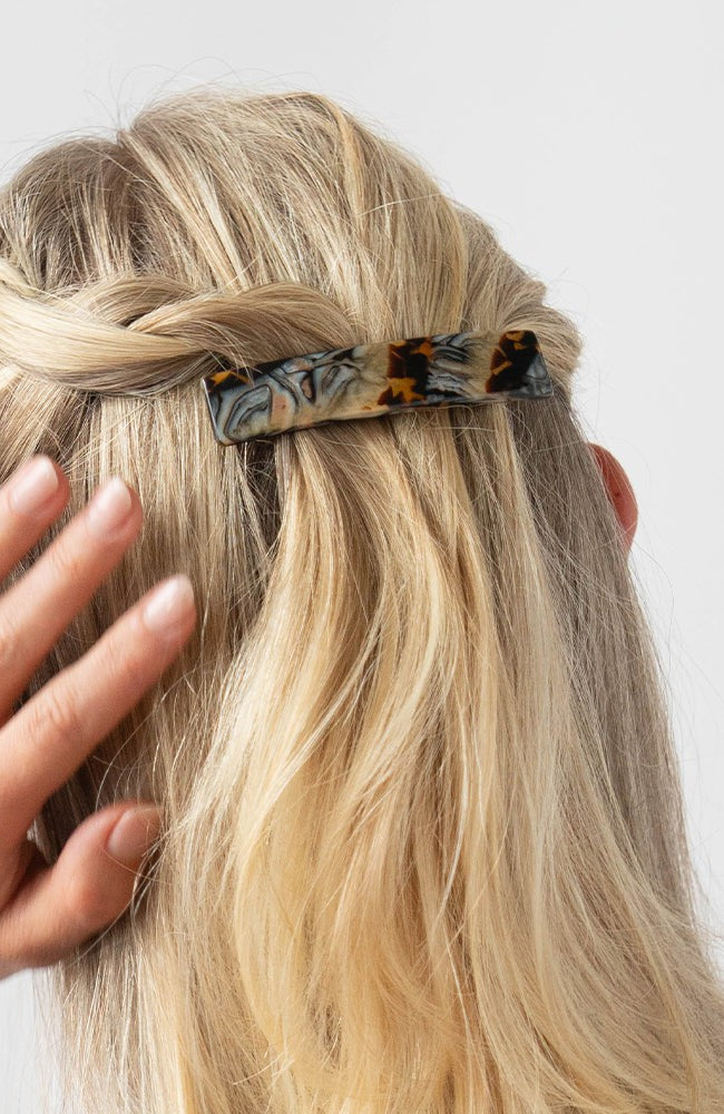 France Luxe medium French barrette for women pictured holding straight, blonde hair in a braided hairstyle.