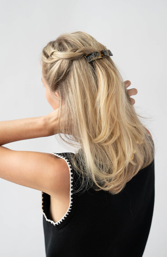 France Luxe medium French barrette for women pictured holding straight, blonde hair in a braided hairstyle.
