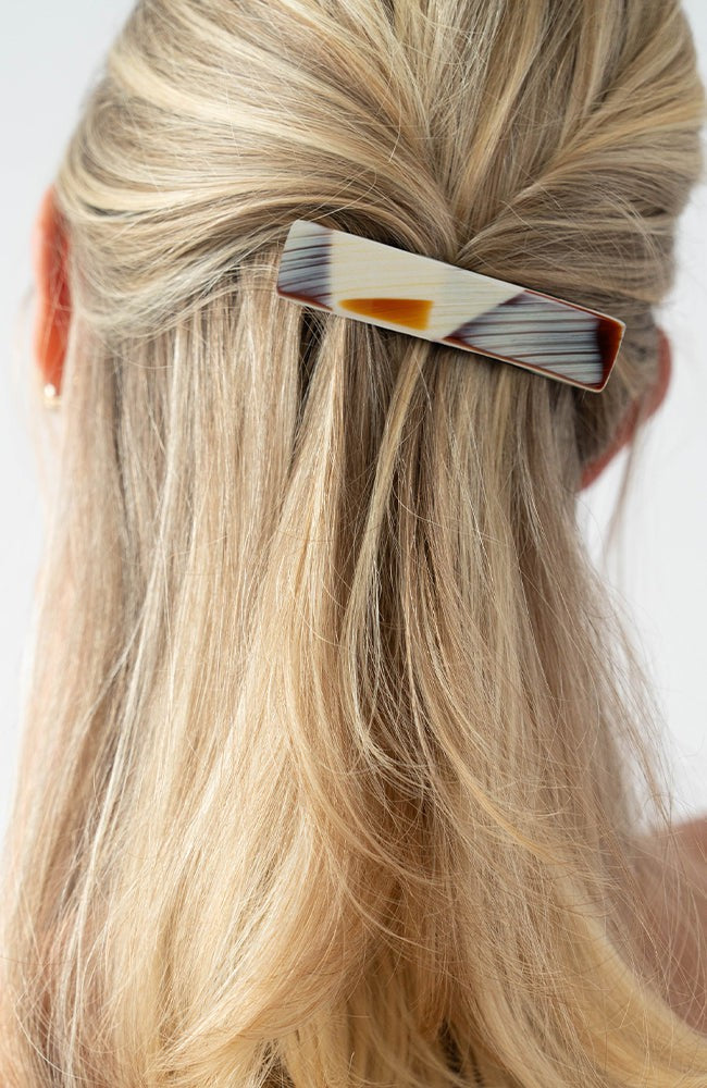 France Luxe medium, brown barrette for women pictured holding straight, blonde hair in a half up hairstyle.
