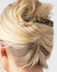 Woman with straight, blonde hair styled in a twist updo with a France Luxe medium, Grey barrette.
