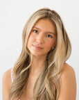 France Luxe thin headband in a checkered tortoise and ivory color, pictured holding straight, blonde hair in a loose hairstyle.