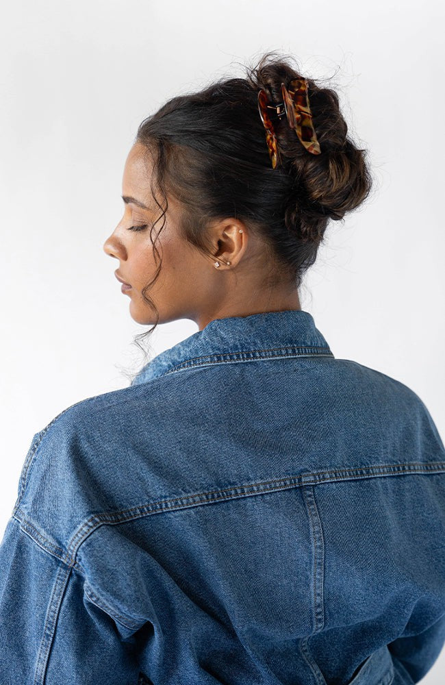 Woman with curly, brown hair styled in a bun with a France Luxe medium claw hair clip, textured bronze and amber.