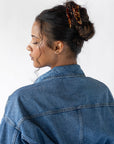 Woman with curly, brown hair styled in a bun with a France Luxe medium claw hair clip, textured bronze and amber.