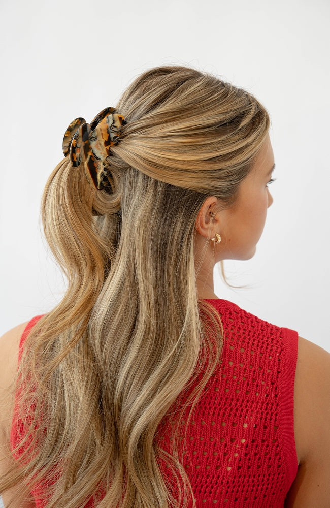France Luxe medium, brown claw hair clip for women pictured holding straight, blonde hair in a half up hairstyle.