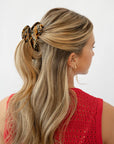 France Luxe medium, brown claw hair clip for women pictured holding straight, blonde hair in a half up hairstyle.