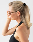 France Luxe mini French claw hair clip for women pictured holding straight, blonde hair in a half up hairstyle.
