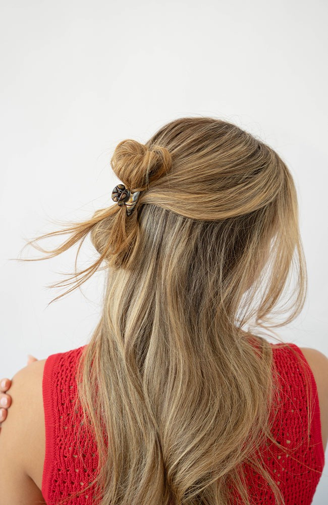 France Luxe mini, grey, claw hair clip for women pictured holding straight, blonde hair in a half up twist hairstyle.