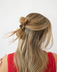 France Luxe mini, grey, claw hair clip for women pictured holding straight, blonde hair in a half up twist hairstyle.