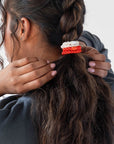 L. Erickson Orange & White, no damage hair ties, styling dark brown, curly, dutch braid ponytail.