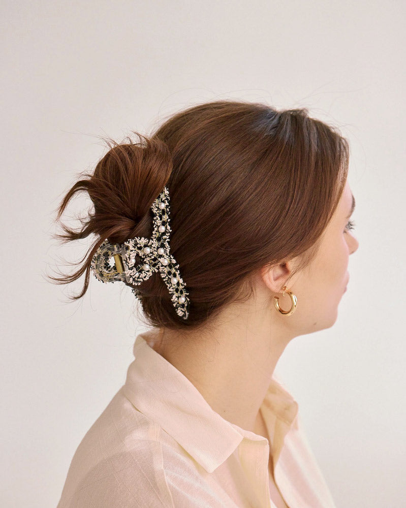 Twisted jaw hair clip features tweed fringe accented with white faux pearls. Hair clip is pictured in straight brown hair.